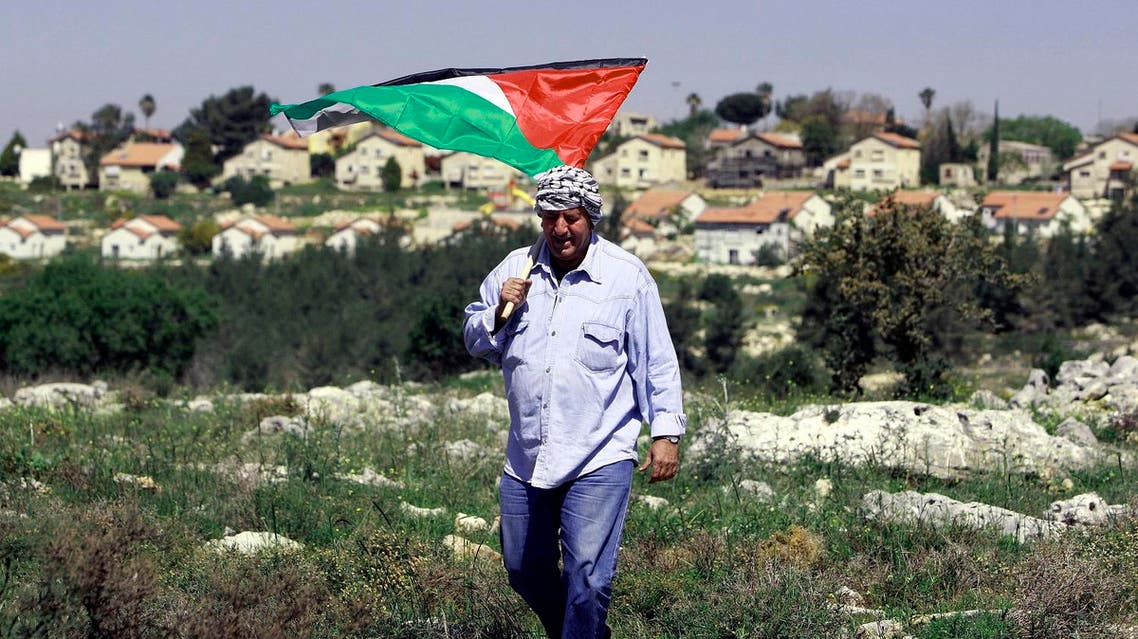 A Palestinian man holds the national flag during a rally marking the Land Day close to the Jewish settlement of Mavo Dothan, south Jenin city, Monday, March 31, 2014. (AP)