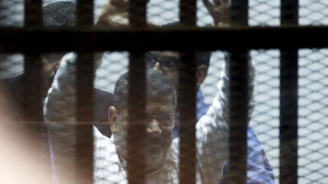 Ousted Egyptian President Mohamed Mursi gestures after his trial behind bars at a court in the outskirts of Cairo, April 21, 2015. An Egyptian court sentenced ousted President Mohamed Mursi to 20 years in prison without parole on Tuesday for the killing of protesters in December 2012, in a decision broadcast on state television. REUTERS