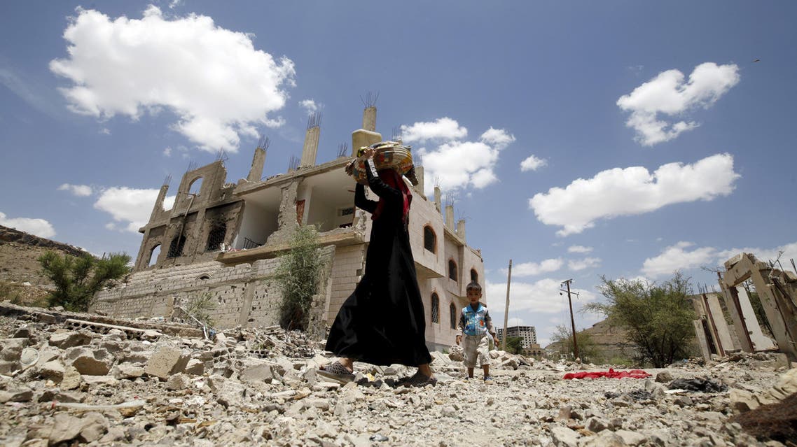 A woman and a boy walk past the ruins of buildings destroyed in Saudi-led air strikes in Yemen's capital Sanaa, September 13, 2015.