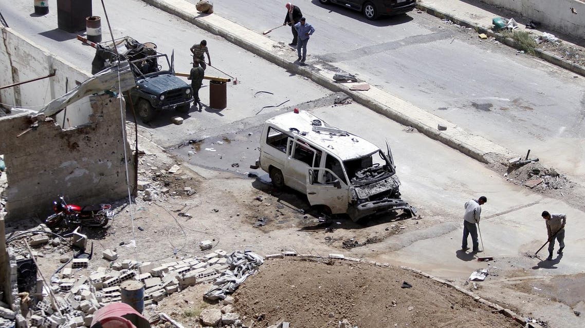 Workers clean a street at the site of a car bomb on the outskirts of the Sayeda Zeinab district south of Damascus, Syria, April 25, 2016. REUTERS