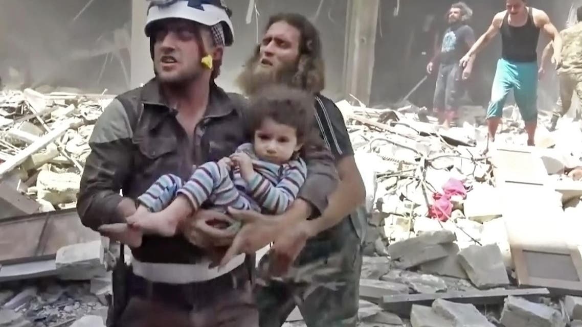 In this image made from video and posted online from Validated UGC, a Civil Defense worker carries a child after airstrikes hit Aleppo, Syria, Thursday, April 28, 2016. A Syrian monitoring group and a first-responders team say new airstrikes on the rebel-held part of the contested city of Aleppo have killed over a dozen people and brought down at least one residential building. The new violence on Thursday brings the death toll in the past 24-hours in the deeply divided city to at least 61 killed. (Validated UGC via AP video)