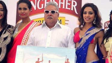 Indian UB Group chairman Vijay Mallya (C, in white) poses with models during the launch of the Kingfisher 2014 calendar in Mumbai on December 21, 2013. (AFP)