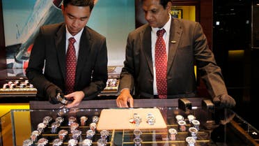 Salesmen show watches to customers at a Breitling watch store at the shopping centre Mall of the Emirates in Dubai, January 11, 2012.