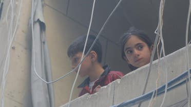 Children look out from a balcony at a site hit by airstrikes, in the rebel-held area of Aleppo's Bustan al-Qasr, Syria April 29, 2016. REUTERS