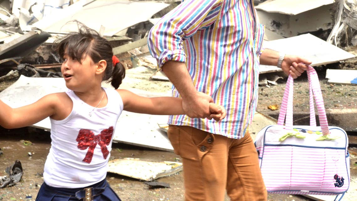 A man holds the hand of a girl as they rush out after rebels bombarded government-held areas of Aleppo. (Reuters)
