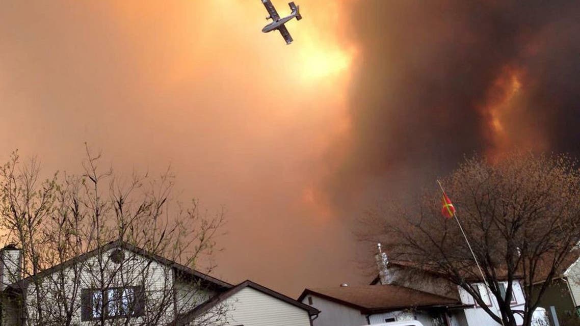 Smoke fills the air as a small plane flies overhead in Fort McMurray, Alberta