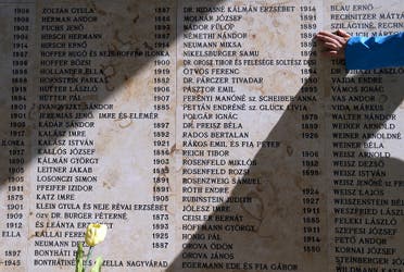 A woman touches a wall with names of Holocaust victims during a funeral of the remains of Holocaust victims in the Jewish cemetery in Budapest, Hungary April 15, 2016. (Reuters)