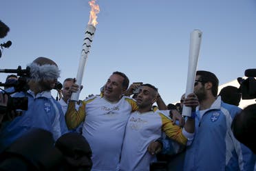 President of the Hellenic Olympic Committee Spiros Kapralos (2nd L) hands over the Olympic Flame to Syrian refugee Ibrahim al-Hussein (2nd R), an amputee swimmer, during the Olympic Flame torch relay at the Eleonas refugee camp in Athens, Greece, April 26, 2016. (Reuters)