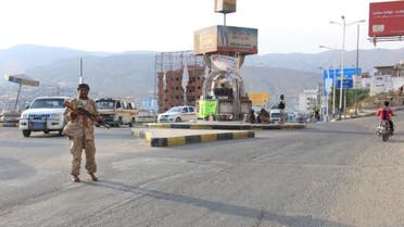 A picture taken on May 3, 2016 shows a Yemeni security forces member patrolling a street with a banner hung by Al-Qaeda militants announcing Islamists' orders of streets seen behind him, in the Yemeni port of Mukalla. (File photo: AFP)