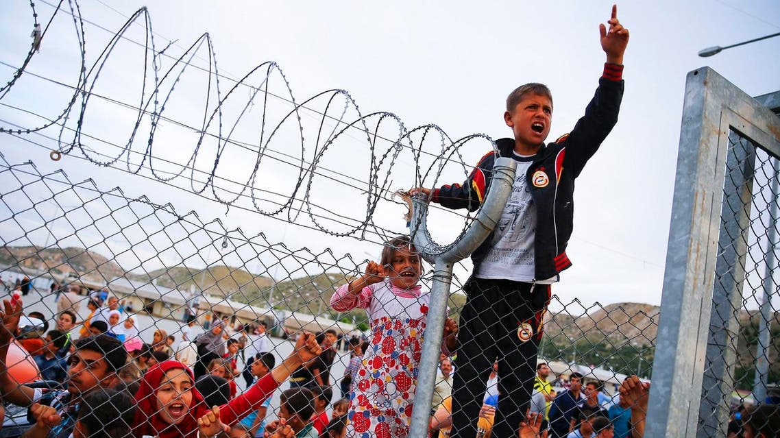 Refugee youths gesture from behind a fence as German Chancellor Angela Merkel, Turkish Prime Minister Ahmet Davutoglu, EU Council President Donald Tusk and European Commission Vice-President Frans Timmermans (all not pictured) arrive at Nizip refugee camp near Gaziantep, Turkey, April 23, 2016. REUTERS