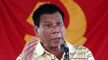 Presidential candidate Mayor Rodrigo Duterte speaks in front of a communist rebel group New People's Army (NPA) flag during the release of five policemen held by the rebels for a week, in Davao city, southern Philippines, April 25, 2016. REUTERS/Keith Bacongco/File Photo SEARCH ÒDUTERTE PRESIDENCYÓ FOR ALL IMAGES