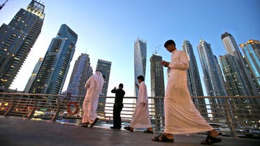 In this April 1, 2015 photo, Gulf Arab visitors in their traditional Kandora pass by giant skyscrapers at the Marina waterfront in Dubai, United Arab Emirates. (AP)
