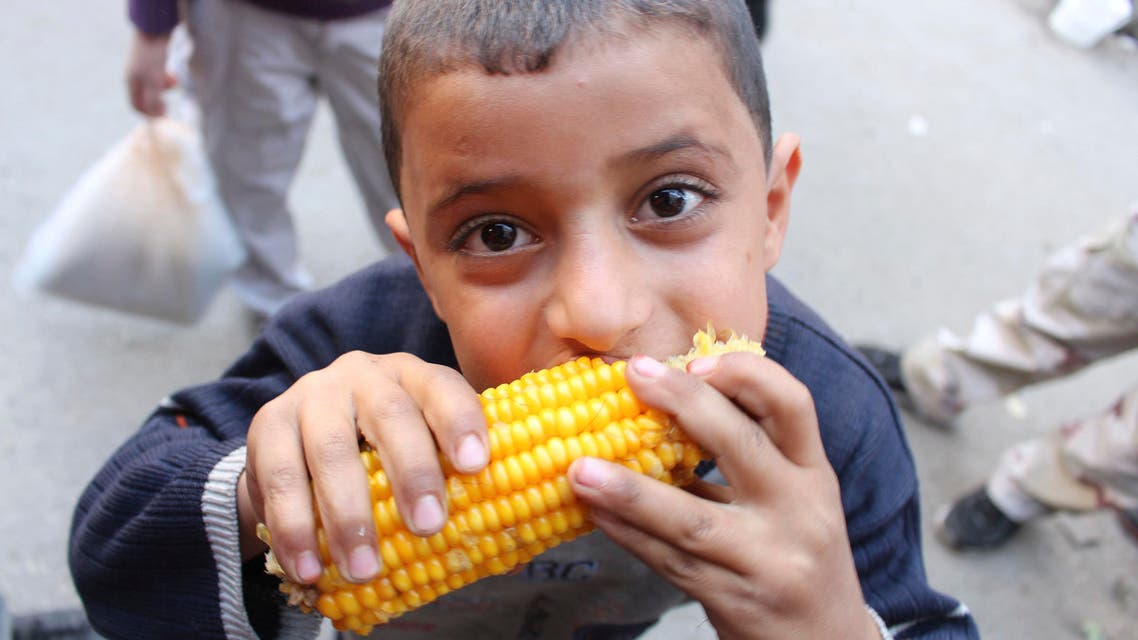 A boy eats maize as people shop ahead of the Muslim festival of Eid-al-Adha in Aleppo October 14, 2013 REUTERS