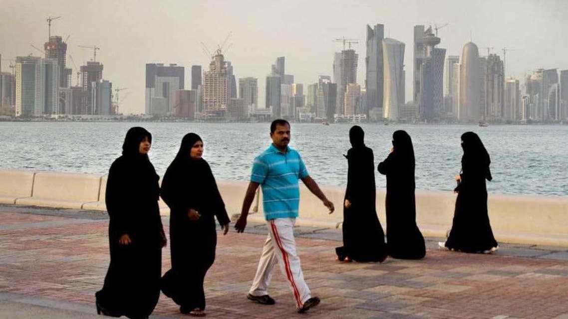 In this Saturday, April 7, 2012 file photo, with the new high-rise buildings of downtown Doha, background, Qatari women and a man walk by the sea in Doha, Qatar. (AP)