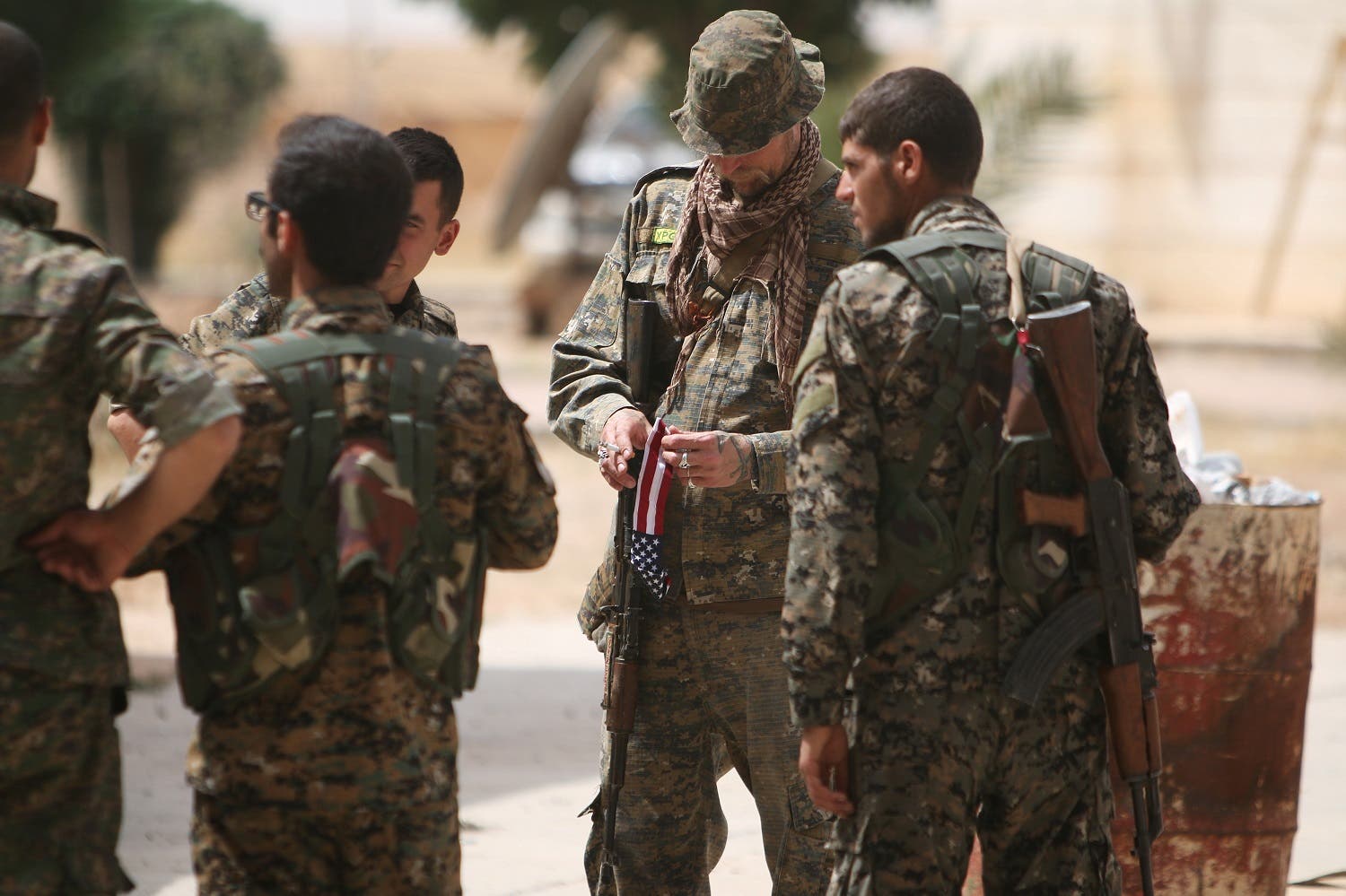 A U.S. fighter, who is fighting alongside with Syria Democratic Forces (SDF), carries his national flag as he stands with SDF fighters in northern province of Raqqa, Syria May 27, 2016. REUTERS