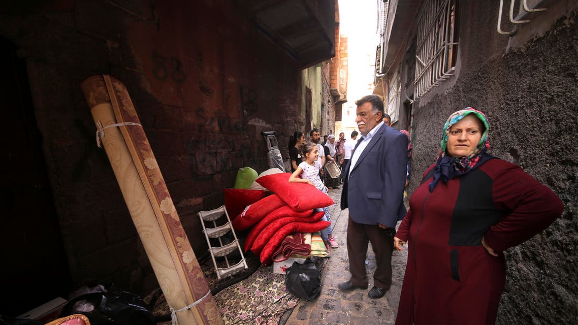 Residents stand by belongings salvaged from their damaged homes in parts of the historic district of the mainly Kurdish city of Diyarbakir, southeastern Turkey, Sunday, May 22, 2016.