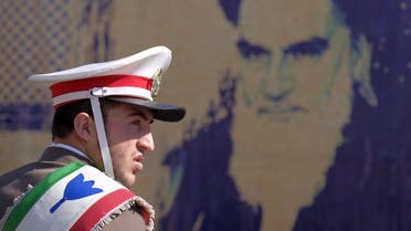 An Iranian soldier stands guard in front of a picture of Iran's late leader Ayatollah Ruhollah Khomeini during the anniversary ceremony of Iran's Islamic Revolution in Behesht Zahra cemetery, south of Tehran, February 1, 2016. (Reuters)