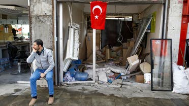 A man sits in front of a damaged shop near the scene of Tuesday's car bomb attack on a police bus, in Istanbul, Turkey