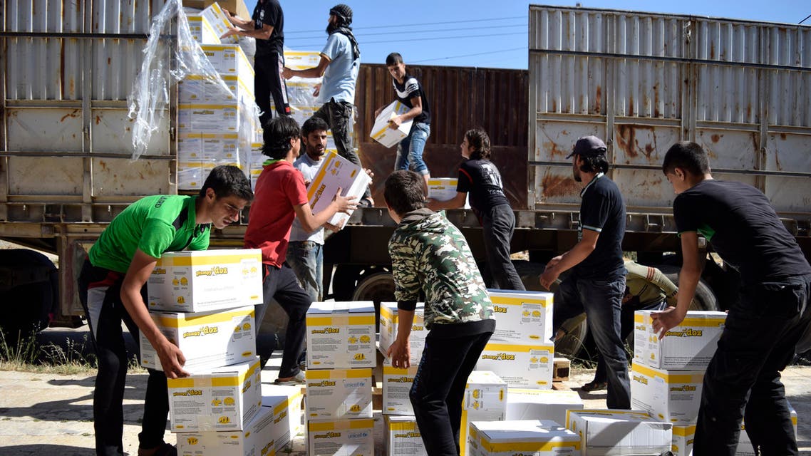 Syrian men carry aid parcels provided by the UN World Food Programm (WFP) and the Syrian Arab Red Crescent in the rebel-held town of Al-Houla, on the northern outskirts of Homs in central Syria, on May 25, 2016. afp