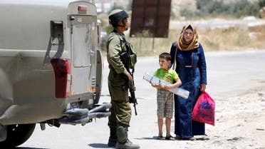 An Israeli soldier stops a Palestinian woman and her son at the entrance of Yatta near the West Bank city of Hebron June 9, 2016. REUTERS