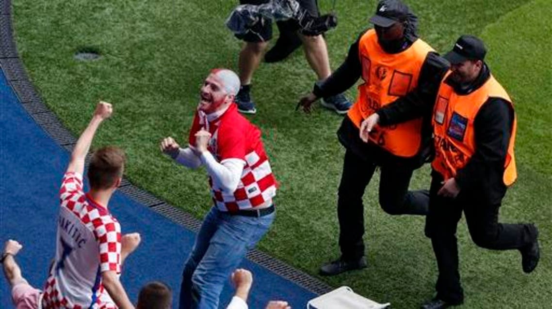 Stewards tray to restrain a Croatian fan who entered the field to celebrate as Croatia's Luka Modric scored his side's first goal during the Euro 2016 Group D soccer match between Turkey and Croatia at the Parc des Princes stadium in Paris, France, Sunday, June 12, 2016. (AP