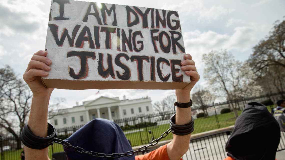 A man dressed as a detainee holds a sign calling attention to the detainees at Guantanamo Bay during a demonstration outside the White House in Washington, Friday, March 11, 2016. (aP)