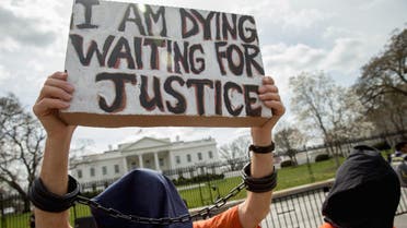 A man dressed as a detainee holds a sign calling attention to the detainees at Guantanamo Bay during a demonstration outside the White House in Washington, Friday, March 11, 2016. (aP)
