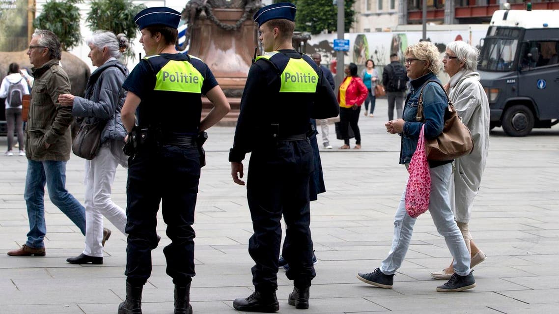 People walk by police standing guard outside the Antwerp Central train station in Antwerp, Belgium on Saturday, June 18, 2016. Police and the bomb squad unit responded to a suspect package in the Antwerp station while the Belgian federal prosecutor's office said early Saturday that homes and car ports were searched in 16 municipalities, mostly in and around Brussels in an anti-terror sweep. (AP Photo/Virginia Mayo)