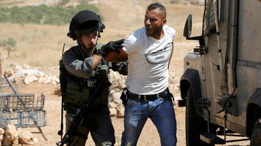 An Israeli border policeman detains a Palestinian man as Israeli troops demolish sheds belonging to Palestinians near the West Bank village of Yatta, south of Hebron June 19, 2016. REUTERS