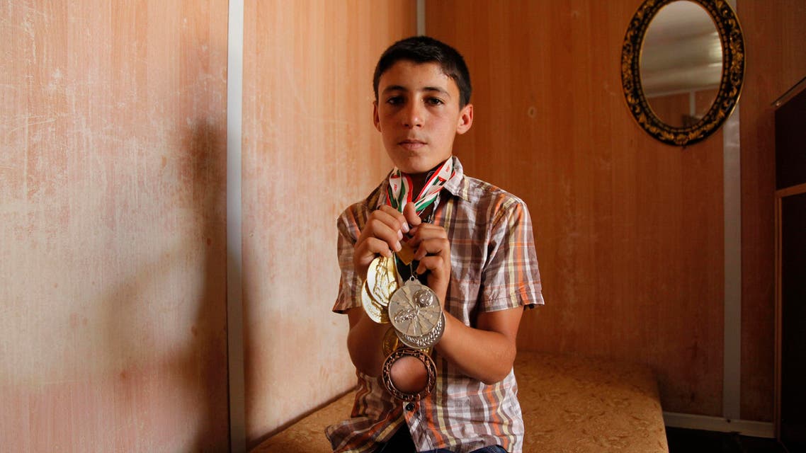 Ayman Ashara, 13, holds gold, silver and bronze medals he's earned playing football in the Zaatari refugee camp, northern Jordan, Sunday, June 19, 2016. (AP)