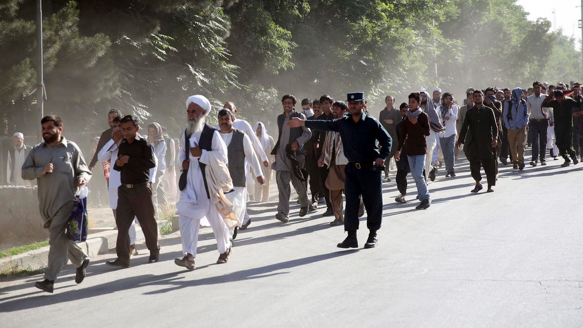 Afghan police officer guides people to walk away at the site of a suicide attack in Kabul, Afghanistan, Monday, June 20, 2016. AP
