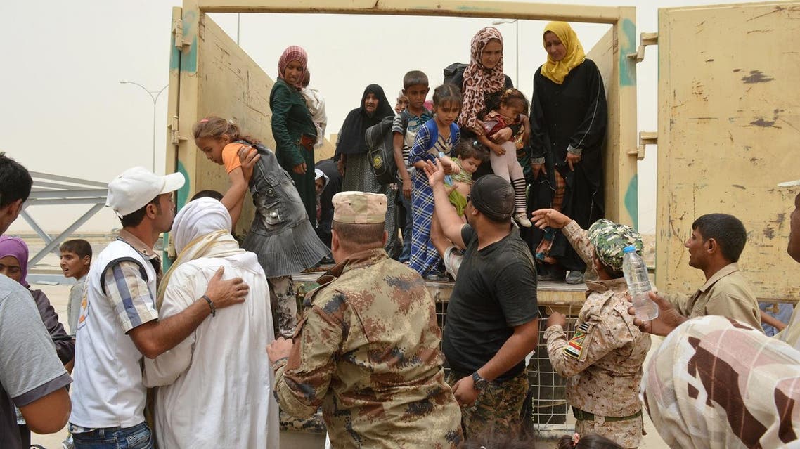 An Iraqi soldier helps civilians, who fled from Falluja because of Islamic State violence, during a dust storm on the outskirts of Falluja, Iraq, June 18, 2016. REUTERS