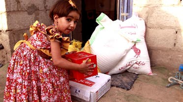 A Yemeni child carries a box as families affected by the country's ongoing conflict receive food rations provided by a local charity during the fasting month of Ramadan on June 15, 2016. (AFP)