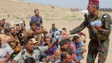 An Iraqi soldier distributes water to displaced Iraqis who were evacuated from their villages by Iraqi government forces south of the besieged Islamic State (IS) group bastion of Fallujah after they arrived at a safe zone in Subayat during a military operation to retake territory from the jihadists on June 12, 2016. AFP