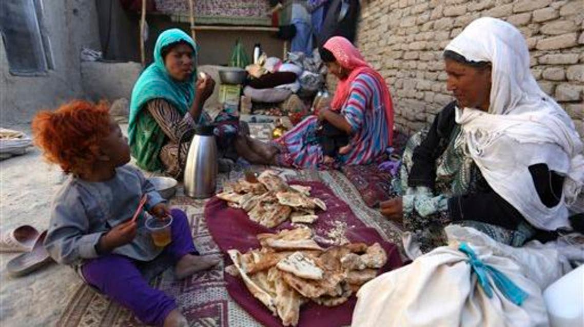 In this Monday, May 30, 2016 photo, an Afghan family take a meal at their temporary home in a camp for internally displaced people in Kabul, Afghanistan. AP
