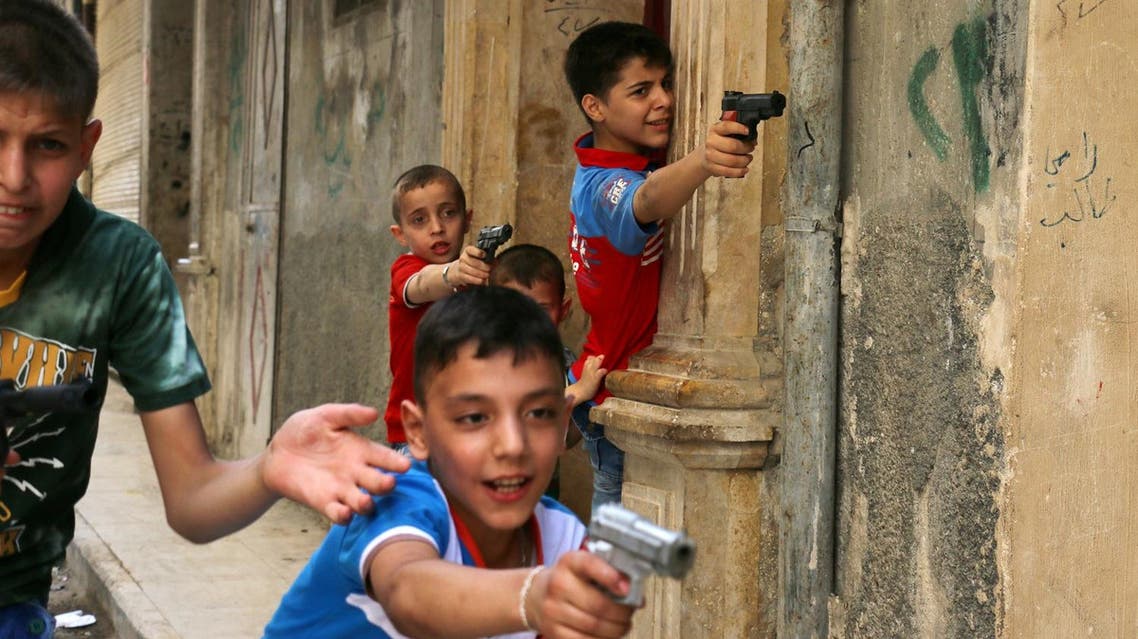 Syrian children play on a street with plastic toy guns in a rebel-held district of the northern city of Aleppo on July 6, 2016 during celebrations for Eid al-Fitr, which marks the end of the Muslim holy fasting month of Ramadan. AMEER ALHALBI / AFP