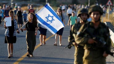 A woman carries the flag of Israel while marching during a protest against the killing of two settlers in the West Bank, July 10, 2016. (Reuters)