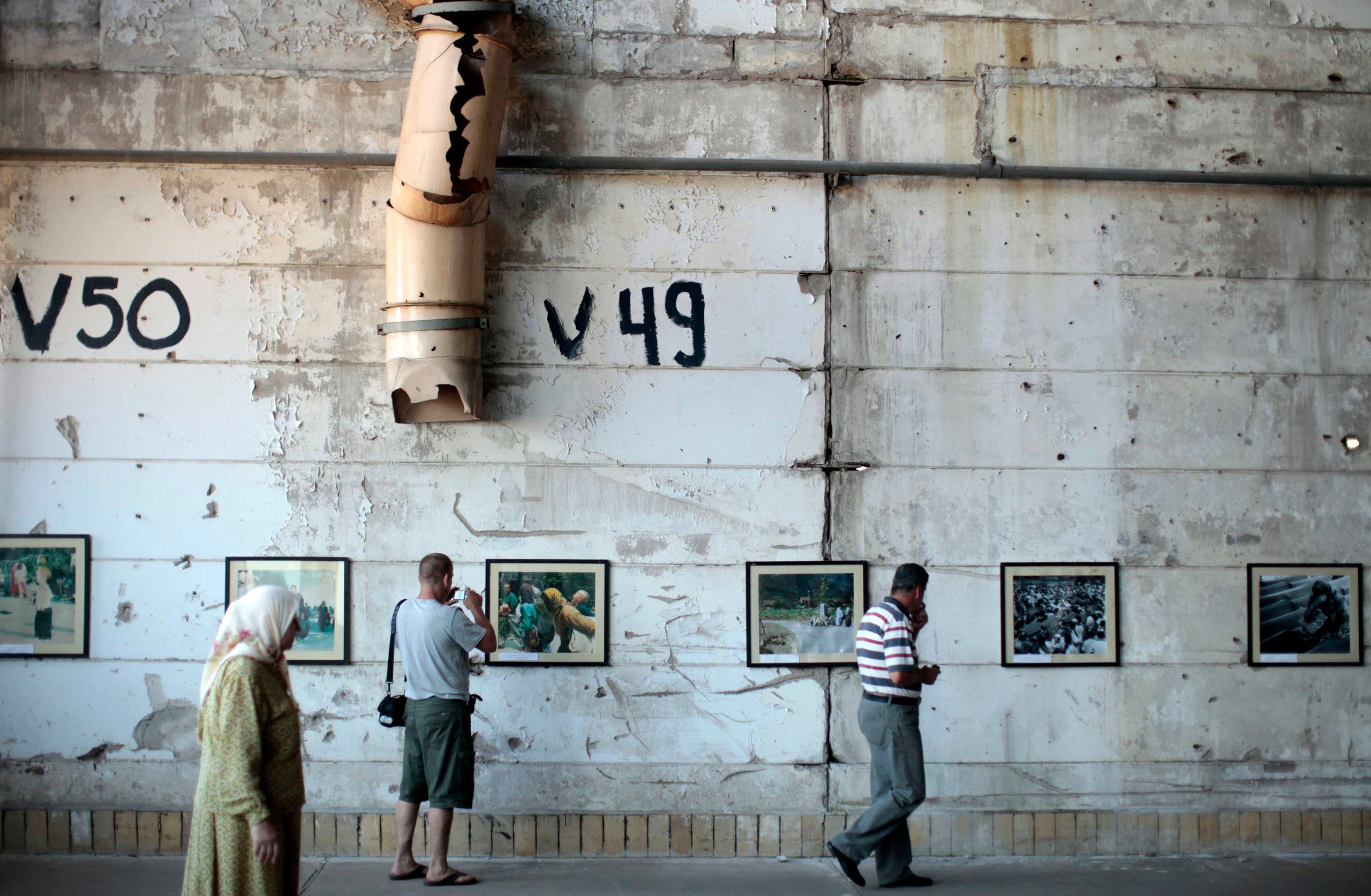 People look at pictures of before and after the war in the Memorial Room Museum in Potocari, near Srebrenica July 3, 2011. (Reuters)