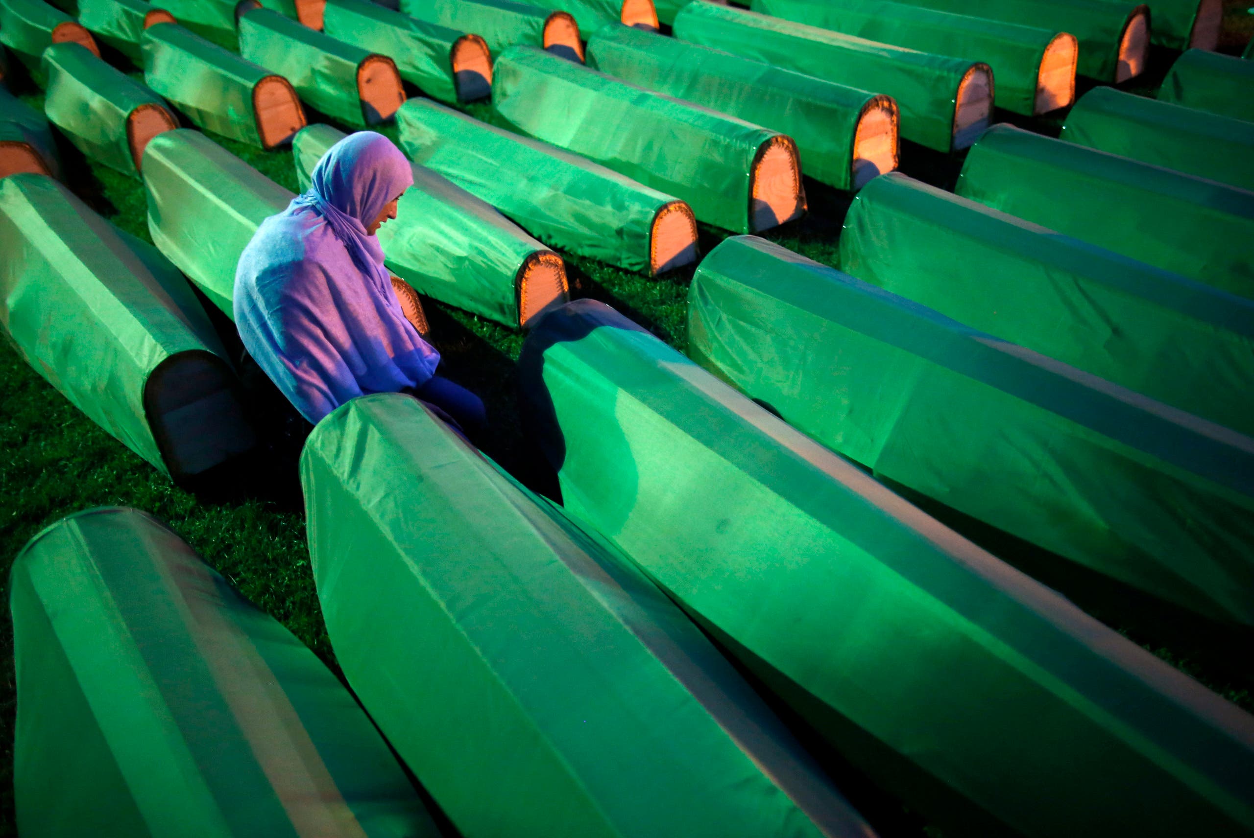 A Bosnian Muslim kneels near the coffin of a relative before a mass funeral for bodies found in a mass grave, in Kozarac, near Prijedor, July 19, 2014. (Reuters)