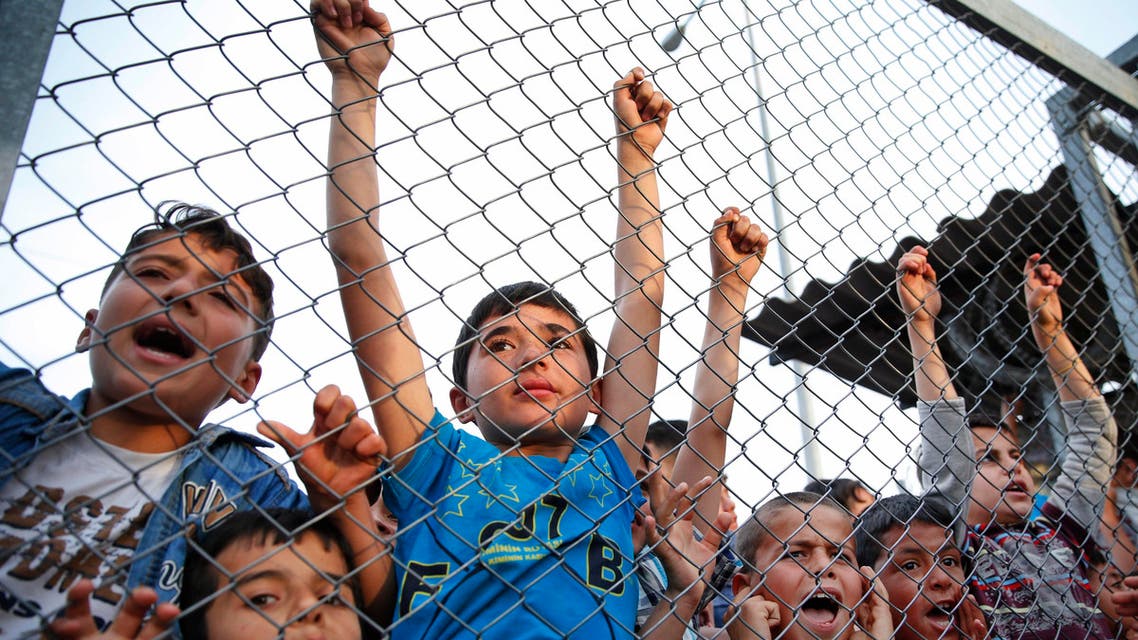 Syrian refugee children chant slogans behind a fence at the Nizip refugee camp in Gaziantep province, southeastern Turkey, following a visit by German Chancellor Angela Merkel and top European Union officials, Saturday, April 23, 2016. (AP)