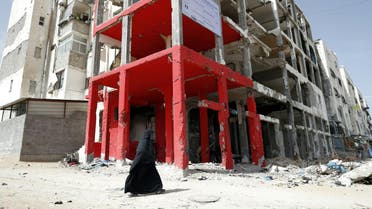 A Palestinian veiled woman walks past a building which was destroyed during the 50-day war between Israel and Hamas-led militants in the summer of 2014, in the northern Gaza Strip city of Beit Hanun, on May 9, 2016.  THOMAS COEX / AFP