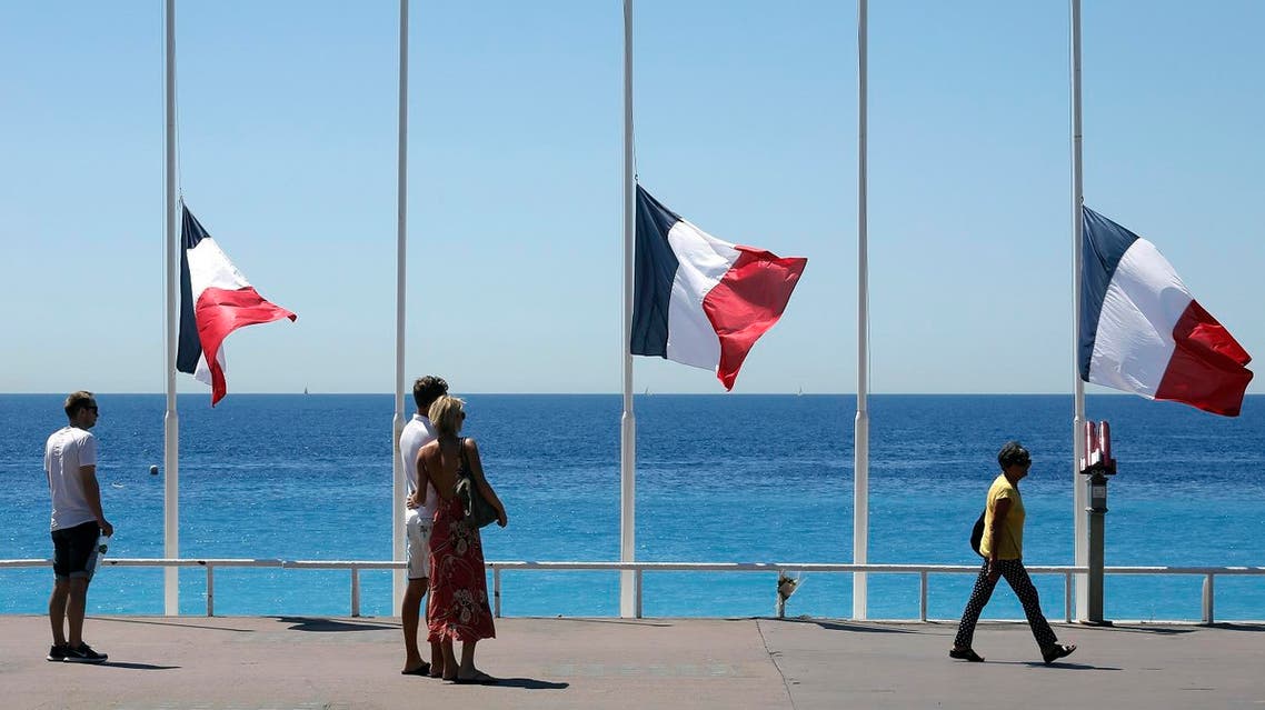 People stroll on the Promenade des Anglais with the French flag at half mast, near the scene of a truck attack in Nice, southern France, Saturday, July 16, 2016. The man responsible for turning a night of celebration into one of carnage in the seaside city of Nice was a petty criminal who hadn't been on the radar of French intelligence services before the attack. (AP Photo/Laurent Cipriani)