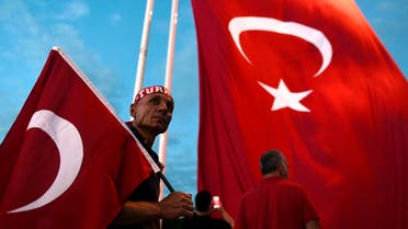 A Pro-Erdogan supporter holds a Turkish national flag as he looks on during a rally at Taksim square in Istanbul. (AFP)
