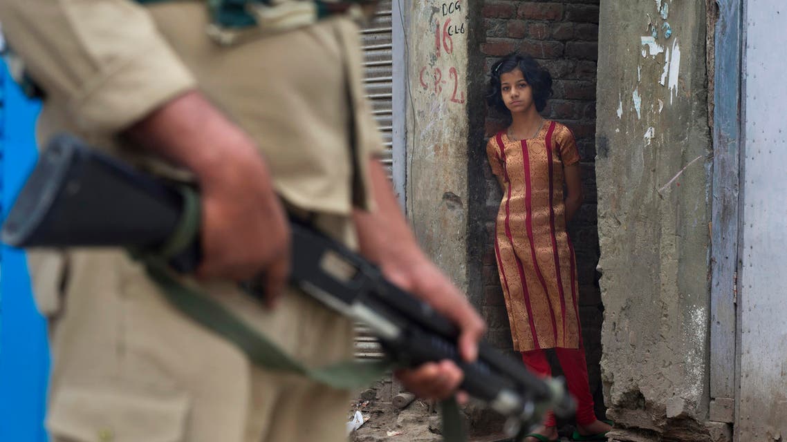 In this Sunday, July 17, 2016 photo, a Kashmiri girl watches an Indian paramilitary soldier standing guard during curfew in Srinagar. (AP)