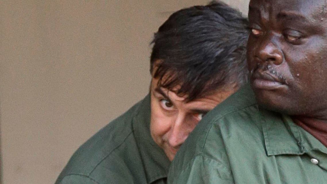 Alexander Fishenko, left, owner of Arc Electronics Inc., hides behind another inmate as they are escorted from the federal courthouse in Houston, Wednesday, Oct. 10, 2012.