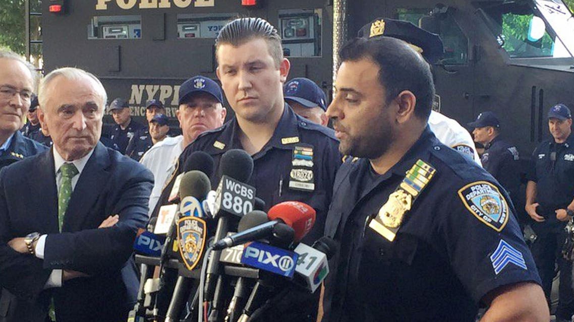 In this photo provided by the New York Police Department (NYPD), Sgt. Hameed Armani, right, and Officer Peter Cybulski talk at a news conference, Thursday, July 21, 2016 at Columbus Circle in New York, about the hoax bomb that was tossed into their police van the night before in Times Square. Police Commissioner William Bratton, left, said, "These two officers are heroes of the NYPD, heroes of New York City." A suspect was taken into custody Thursday. (NYPD via AP )