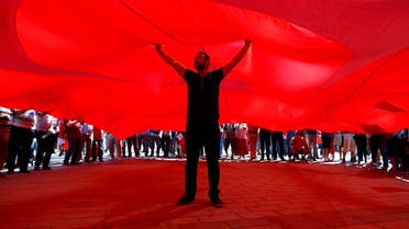 A man stands under the giant Turkey's national flag as supporters of various political parties gather in Istanbul's Taksim Square. (Reuters)