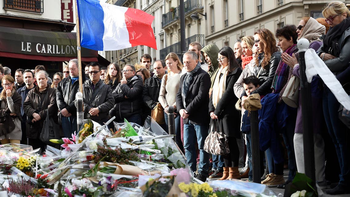 People observe a minute of silence on November 16, 2015 at the Le Carillon cafe at the corner of Rue Bichat and Alibert in the 10th arrondissement and "Le petit Cambodge" restaurant at the site of the attacks in Paris, to pay tribute to victims of the attacks claimed by Islamic State which killed at least 129 people and left more than 350 injured on November 13. AFP PHOTO / ERIC FEFERBERG