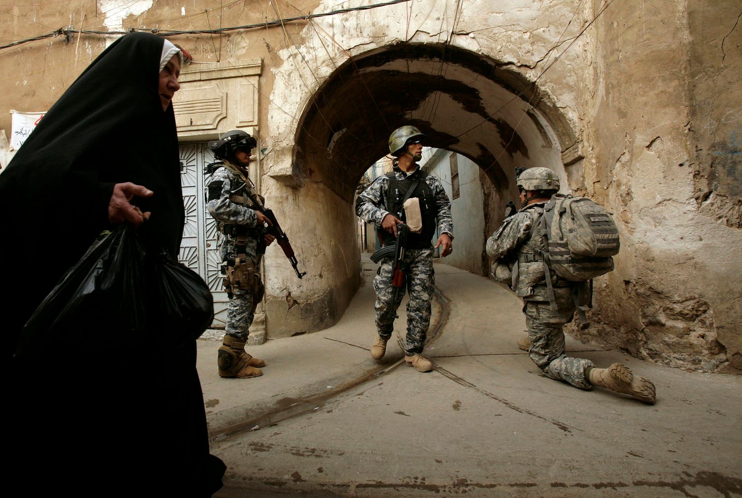 an Iraqi woman passes U.S. troops AP