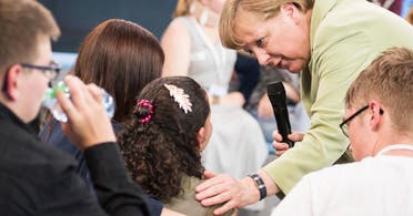 Angela Merkel (R) comforting a a crying Palestinian girl threatened with deportation on July 15, 2015 in Rostock, northern Germany. (AFP)